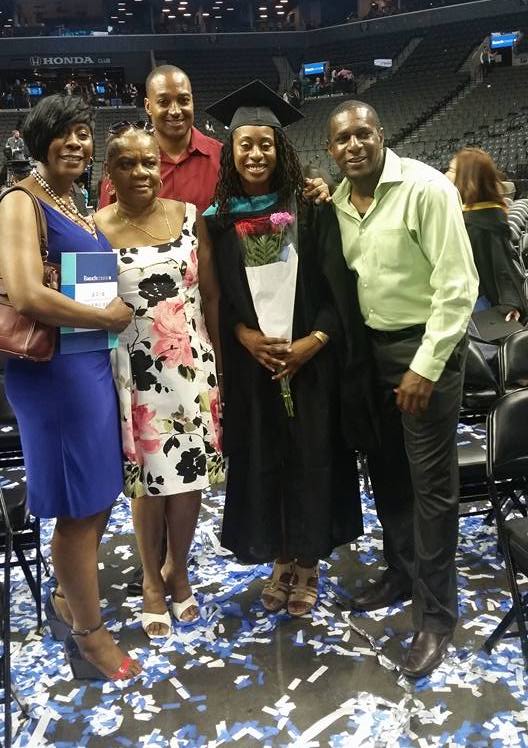 Amoy and her family at her high school graduation. Amoy is in her cap and gown holding a bouqut of flowers.